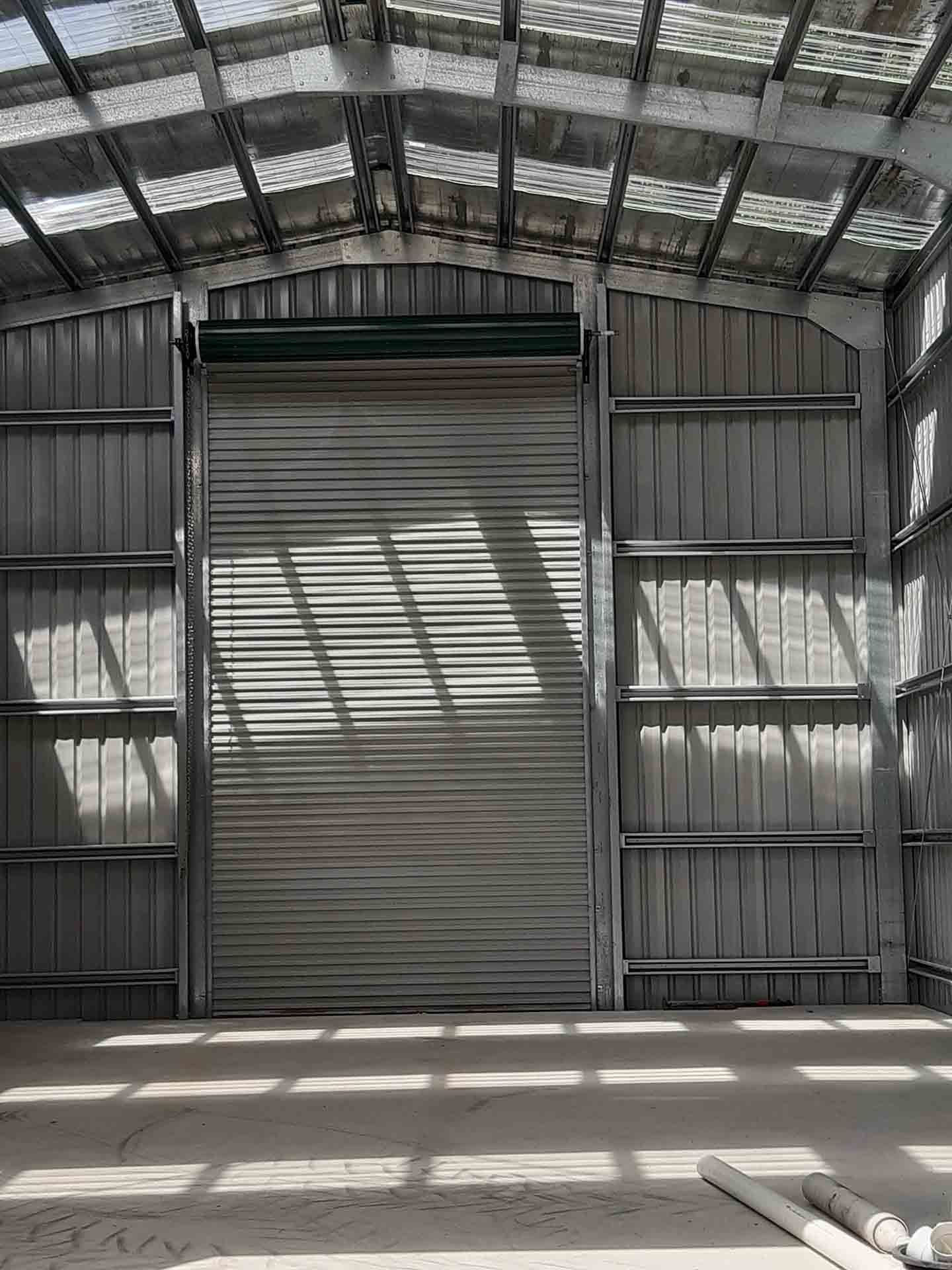 Large Warehouse With A Rolling Door And A Clear Roof — Providing Steel & Concrete Construction In Eviron, NSW