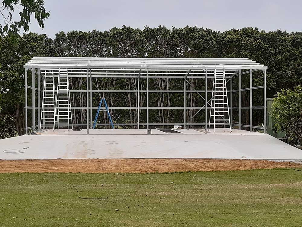 Large Metal Structure Is Being Built In The Middle Of A Grassy Field — Providing Steel & Concrete Construction In Tweed Heads, NSW