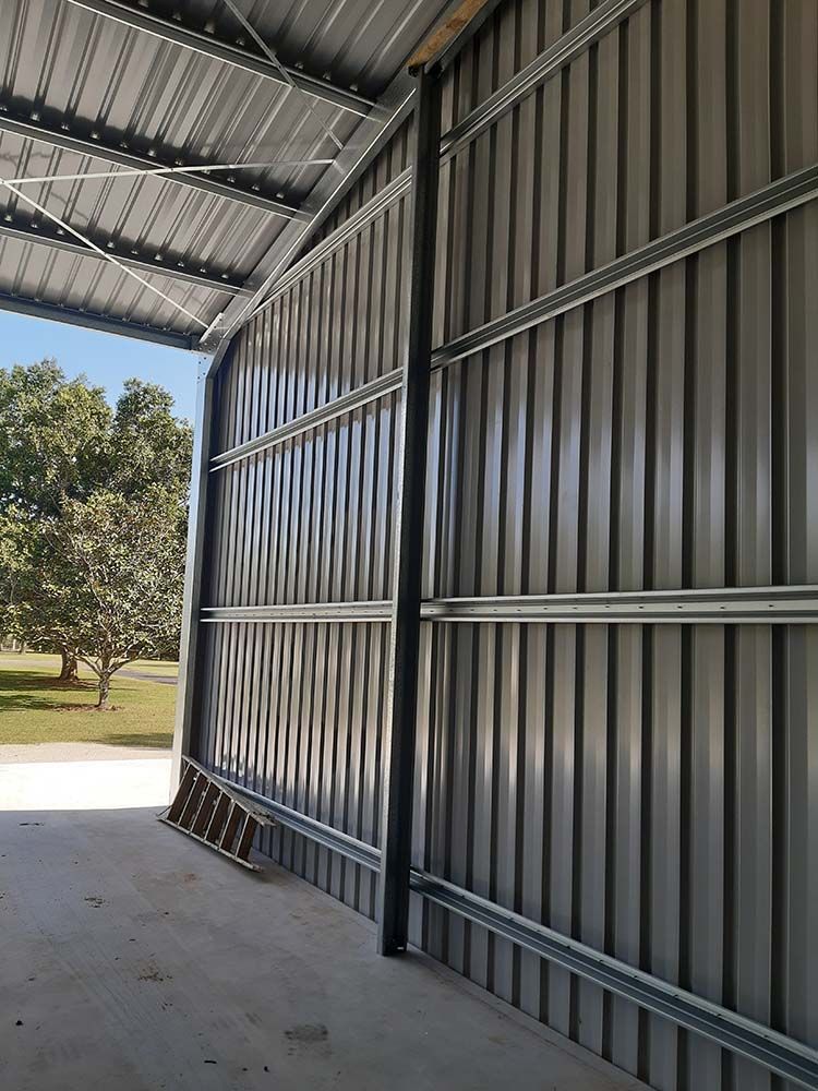 Metal Building With A Ladder On The Ground — Providing Steel & Concrete Construction In Byron Bay, NSW