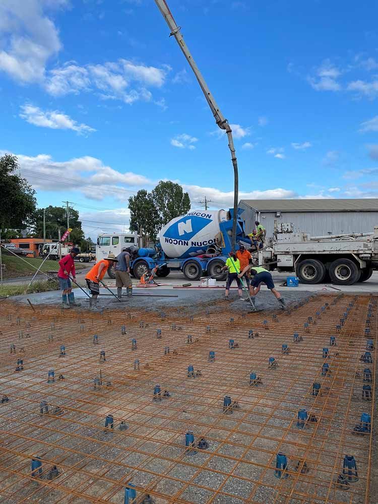 Group Of Construction Workers Are Pouring Concrete On A Construction Site — Providing Steel & Concrete Construction In Byron Bay, NSW