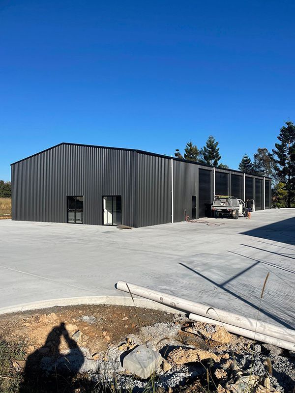 Large empty garage with the door open and a concrete floor — Providing Steel & Concrete Construction In Tweed Heads, NSW