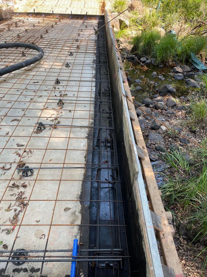 A Concrete Walkway is Being Built Next to a River — Providing Steel & Concrete Construction In Eviron, NSW