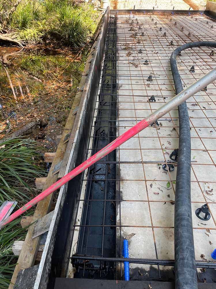 Broom Is Being Used To Clean A Drain On A Construction Site — Providing Steel & Concrete Construction In Gold Coast, QLD