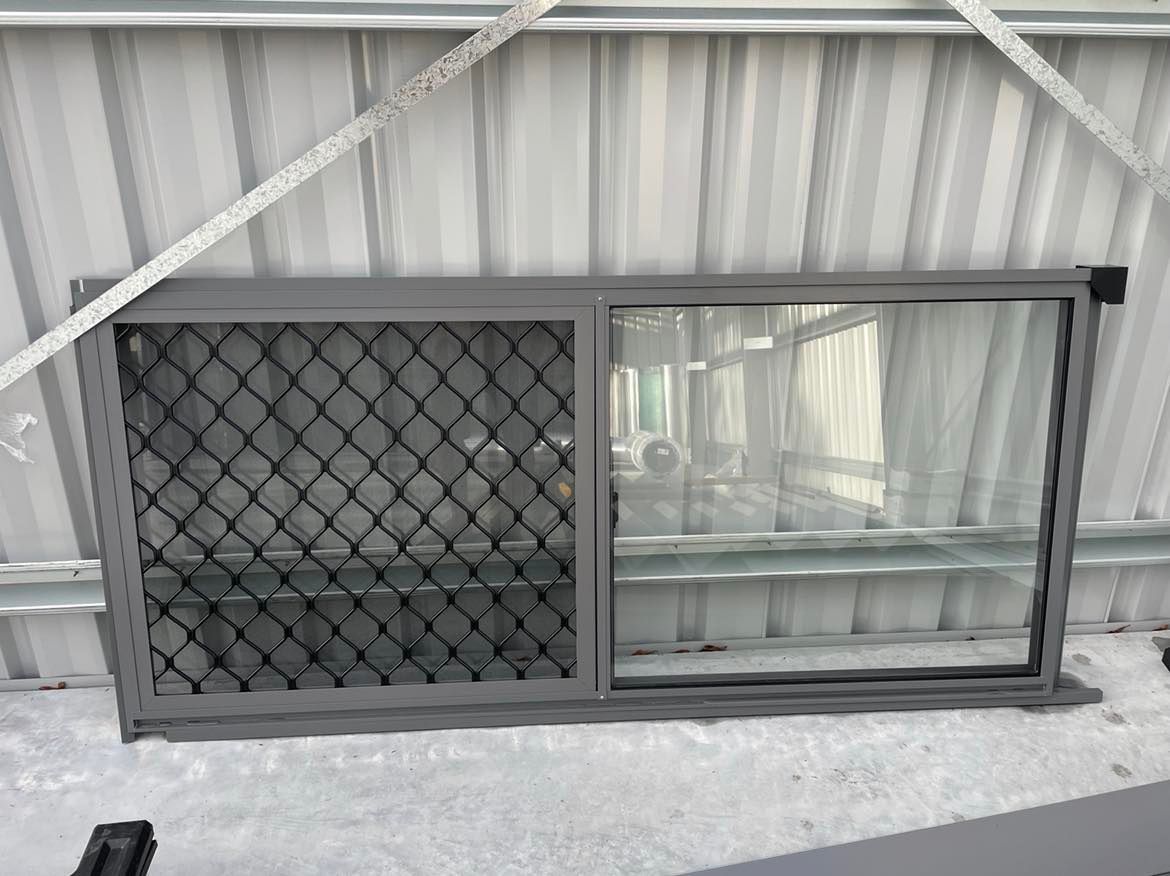 A Window With a Chain Link Fence on It is Sitting on the Ground — Providing Steel & Concrete Construction In Eviron, NSW