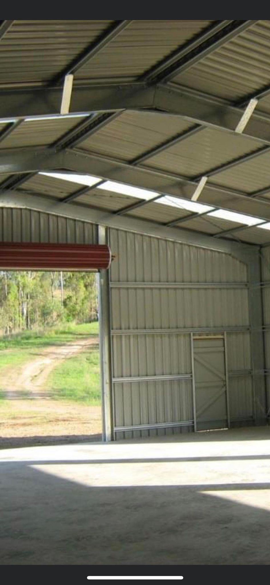 A Large Empty Warehouse With a Large Door Open — Providing Steel & Concrete Construction In Eviron, NSW
