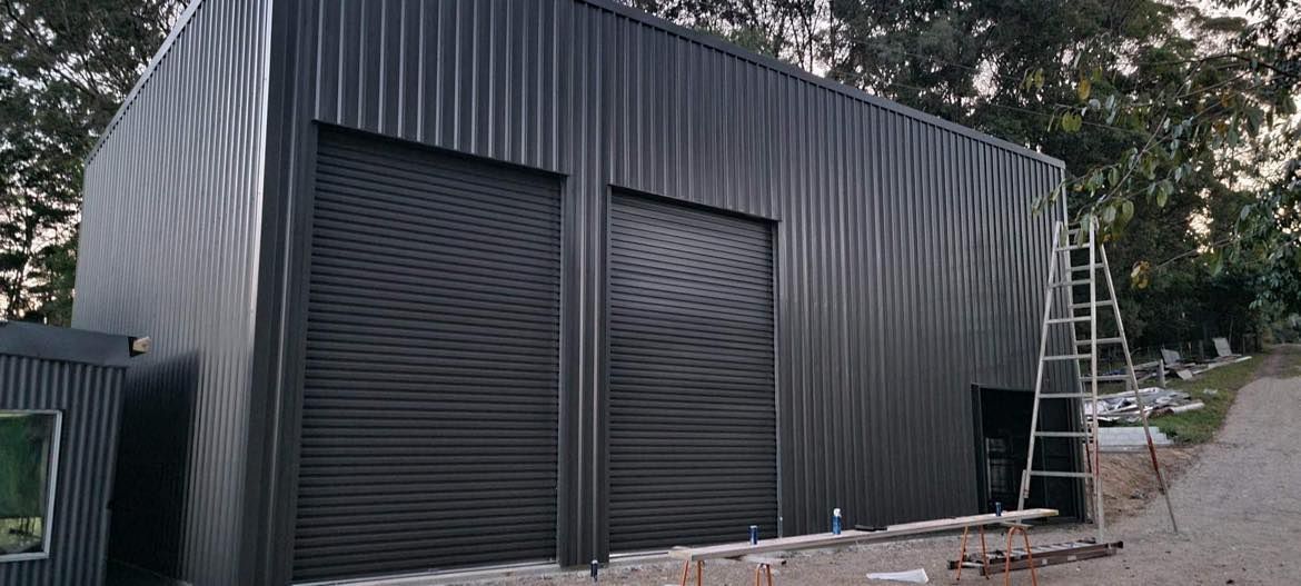 Black Steel Shed with double roller doors — Providing Steel & Concrete Construction In Eviron, NSW