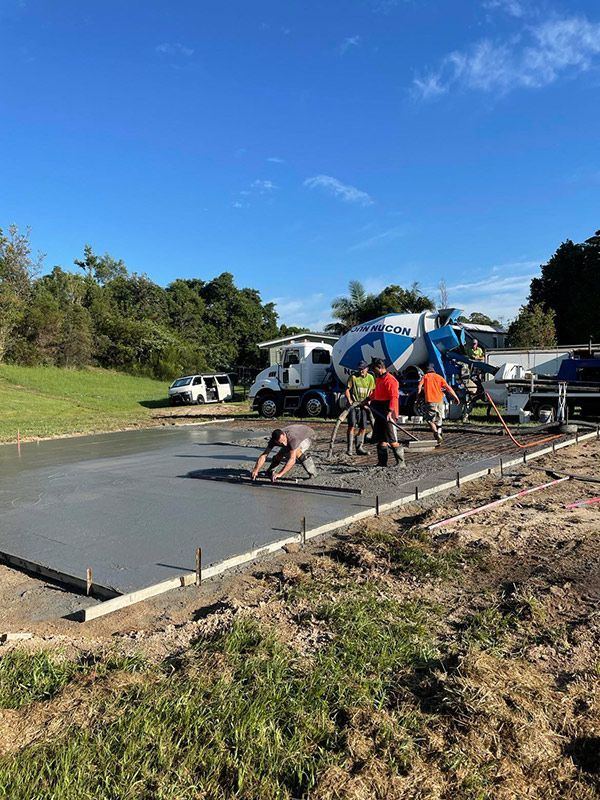 A Group Of People Are Working On A Concrete Driveway With Truck Concrete Mixer — CJR Group Concrete Construction In Byron Bay, NSW