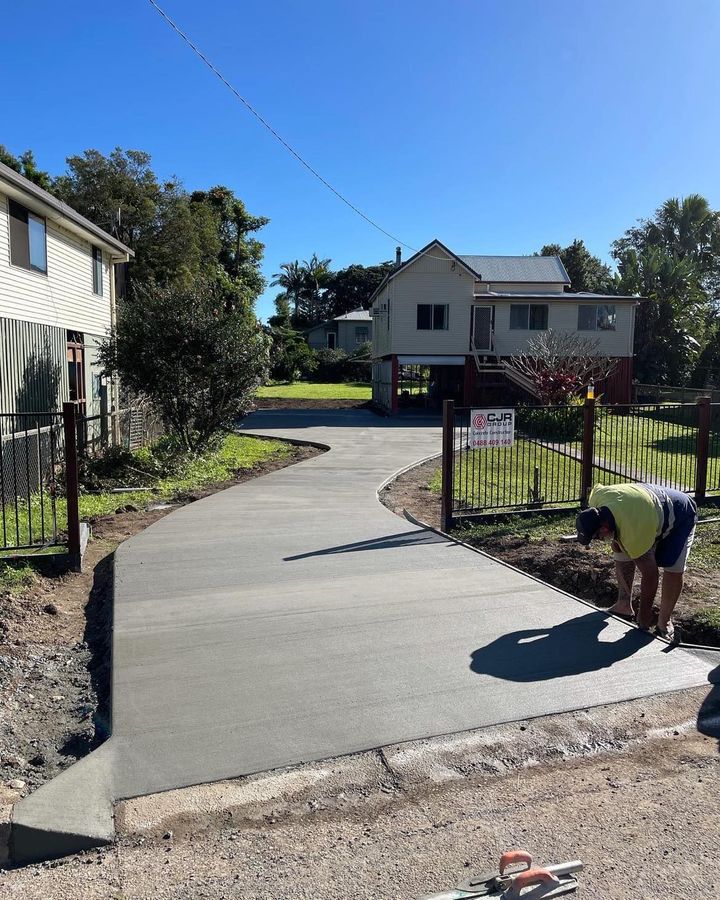A Man is Working on a Concrete Driveway in Front of a House — Providing Steel & Concrete Construction In Eviron, NSW