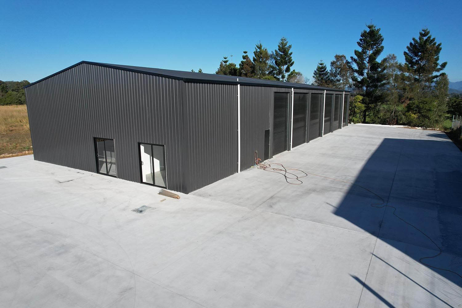 Large Metal Building With A Lot Of Windows And Doors — Providing Steel & Concrete Construction In Byron Bay, NSW