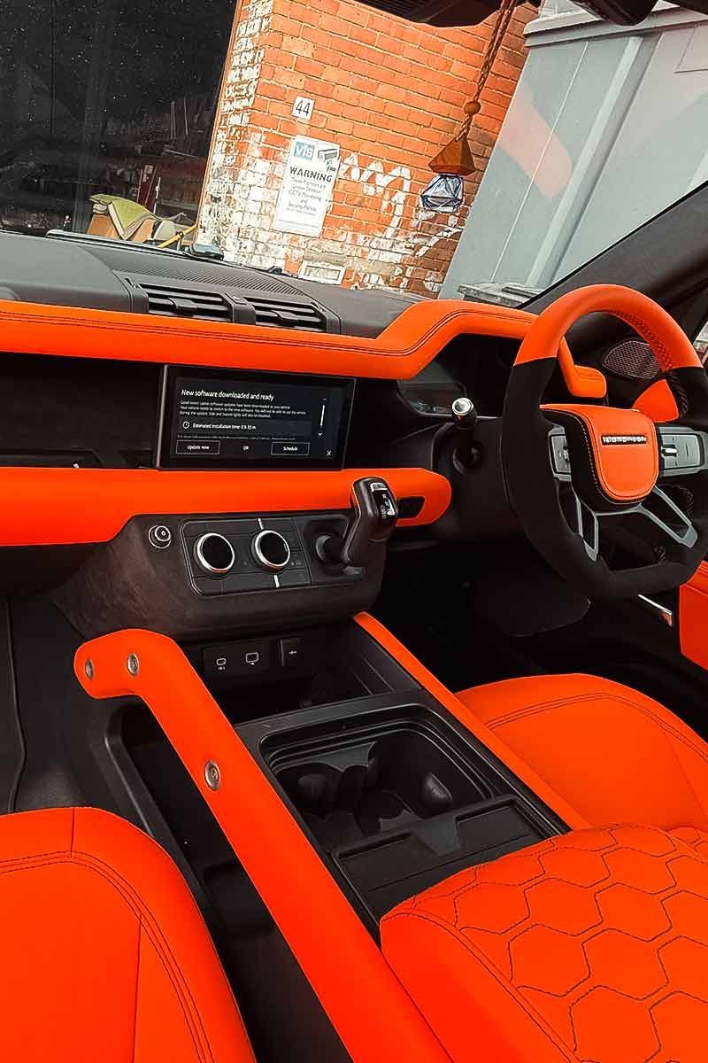 Bright orange car interior with black accents and a steering wheel, viewed from the passenger seat