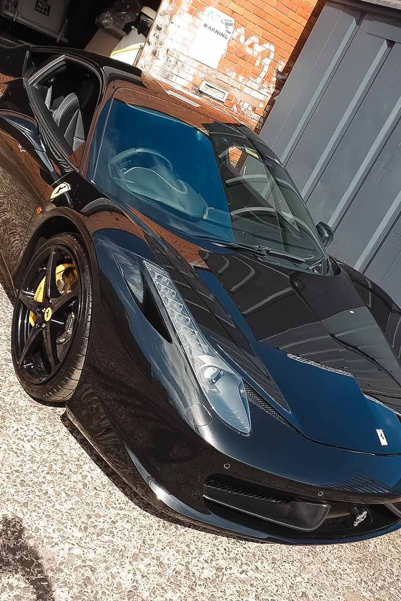 Black sports car with orange accents parked indoors in a garage-like setting