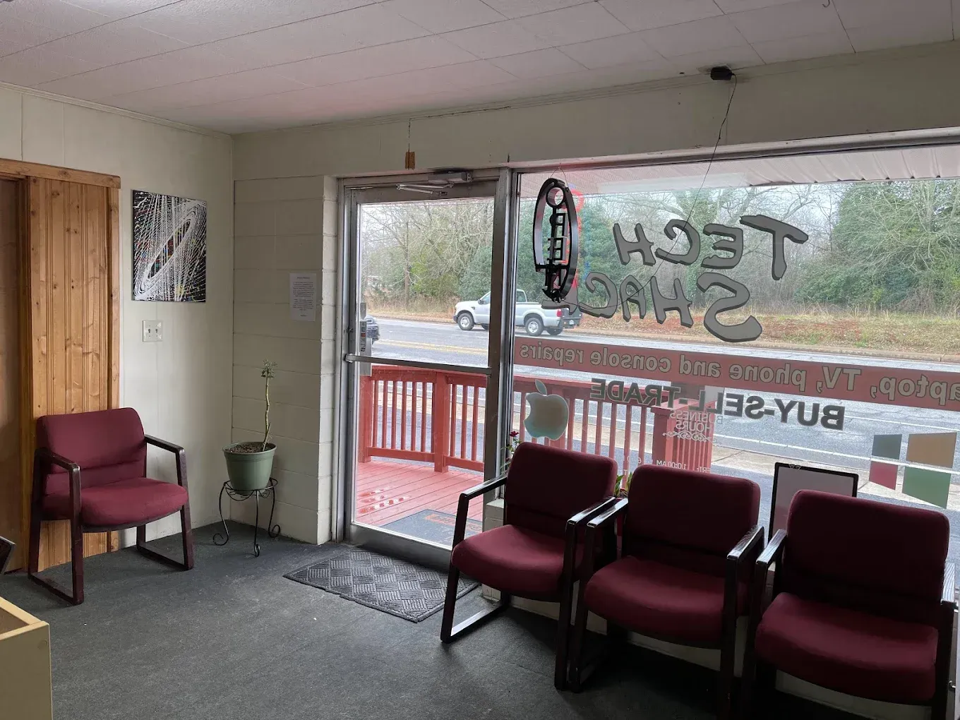 Empty lobby with red chairs, front window, and glass door, viewed from inside a small office entrance.
