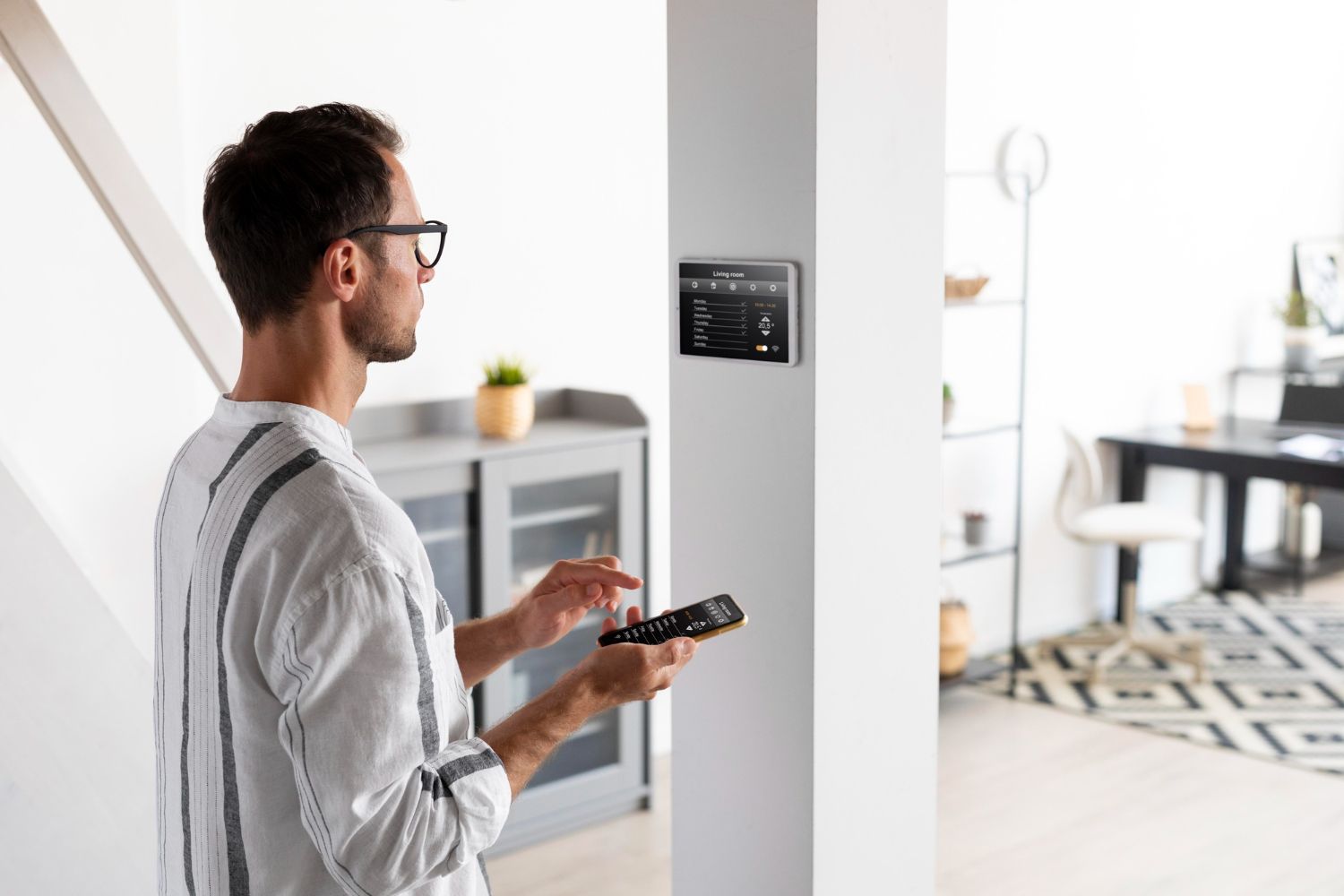 Man controlling a wall-mounted smart home panel in a modern apartment hallway