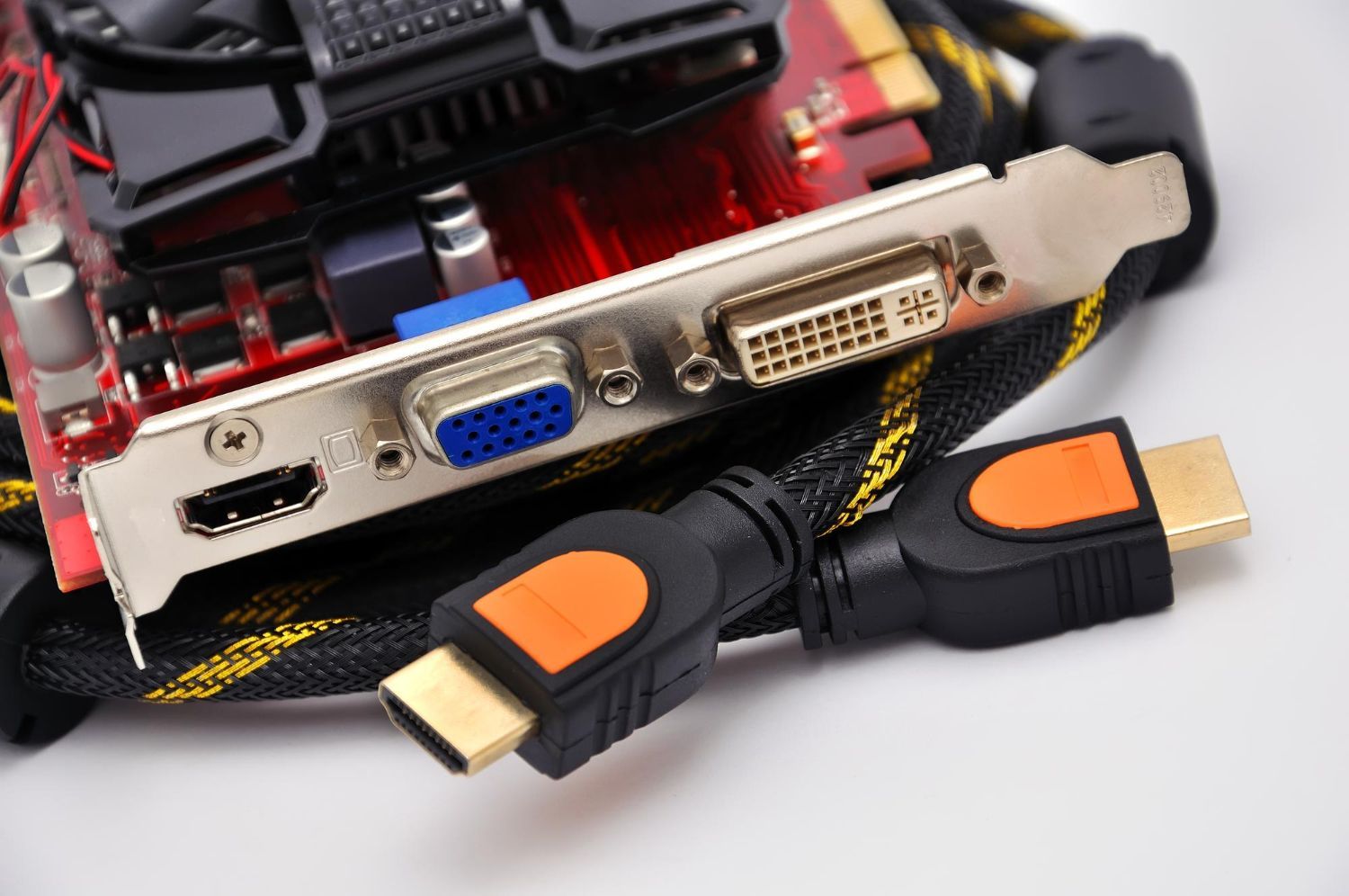 Close-up of a graphics card with HDMI, VGA, DVI ports and two HDMI-to-DVI adapters on a white surface