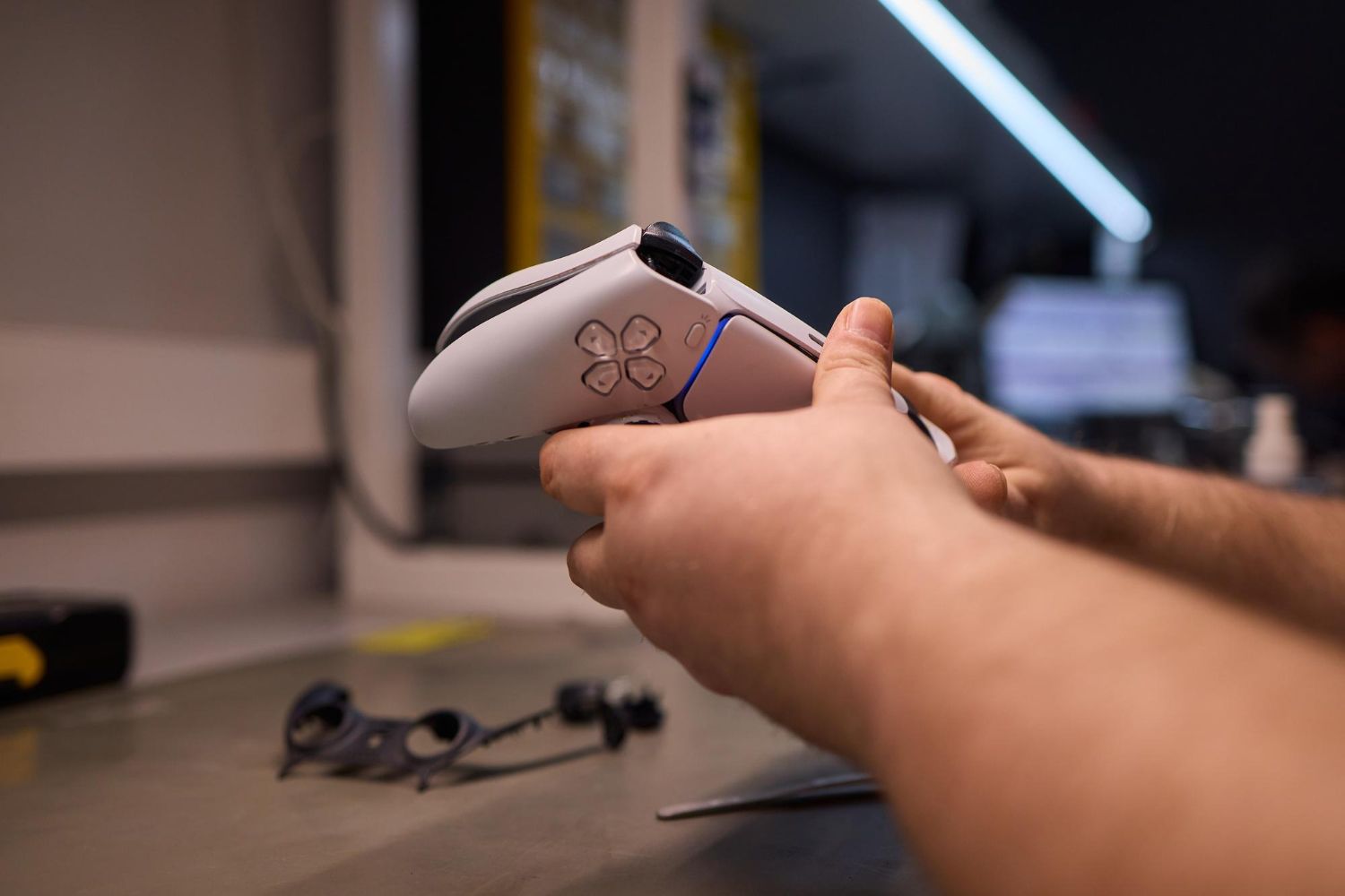 Hands holding a white game controller near a desk with a blurred monitor in the background