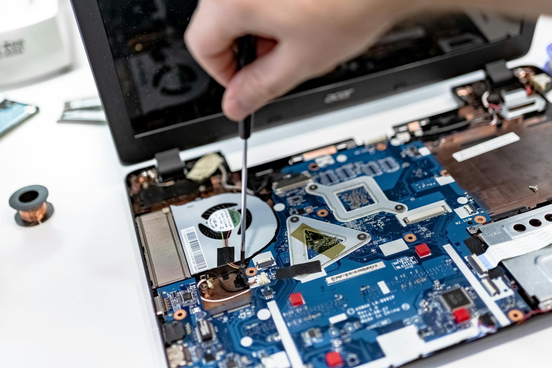Person using a screwdriver to repair a laptop's exposed internal components