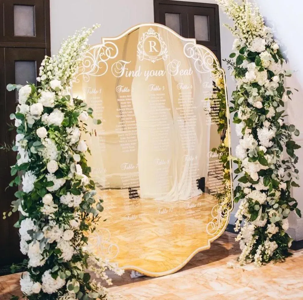 Elegant floral wedding entrance with white flowers, gold arch, and sheer drapes on a marble floor