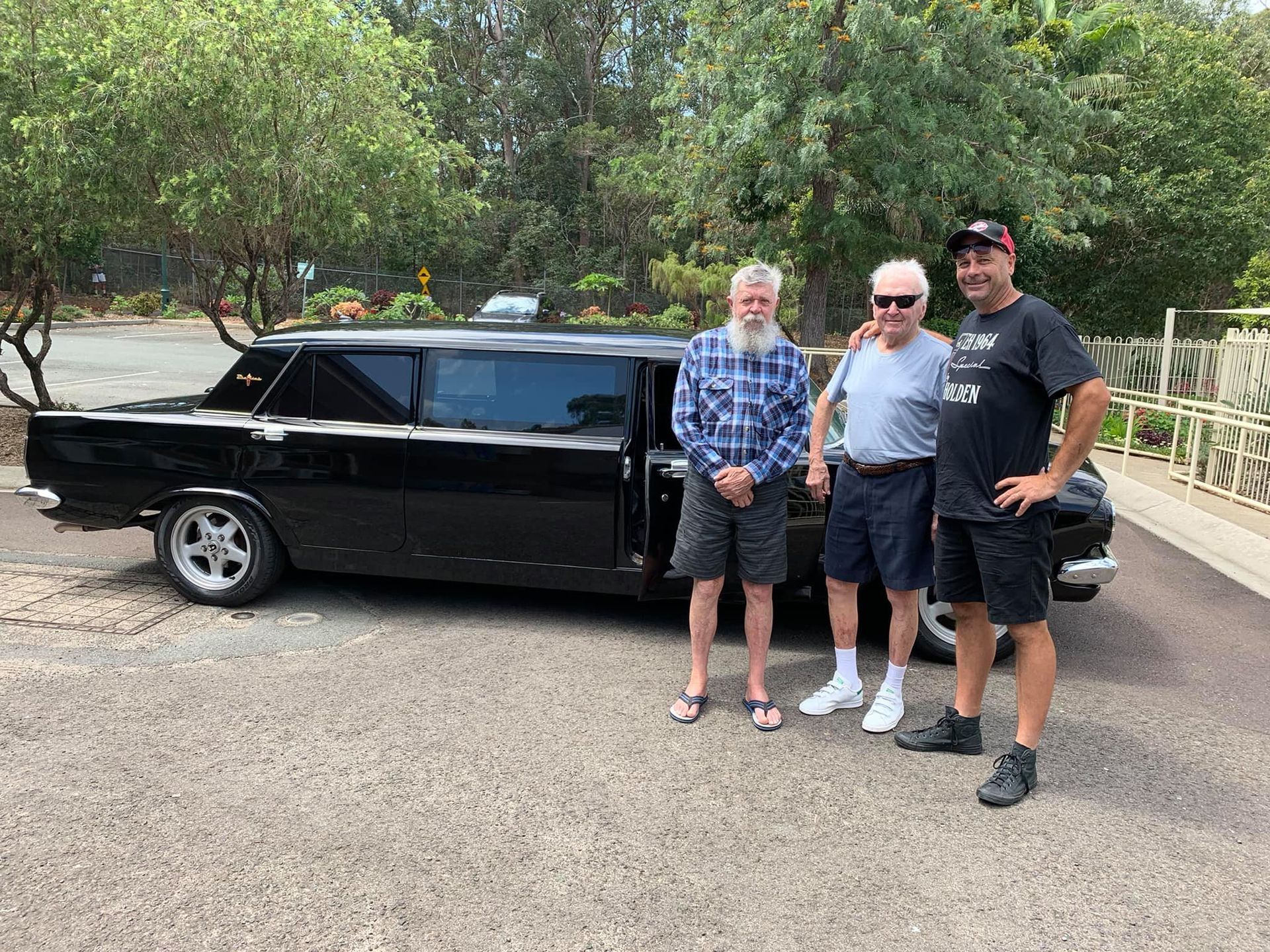 Three Men Are Standing in Front of a Black Limousine — Noosa Premier Stretch Holden Transfers In Sunrise Beach, QLD