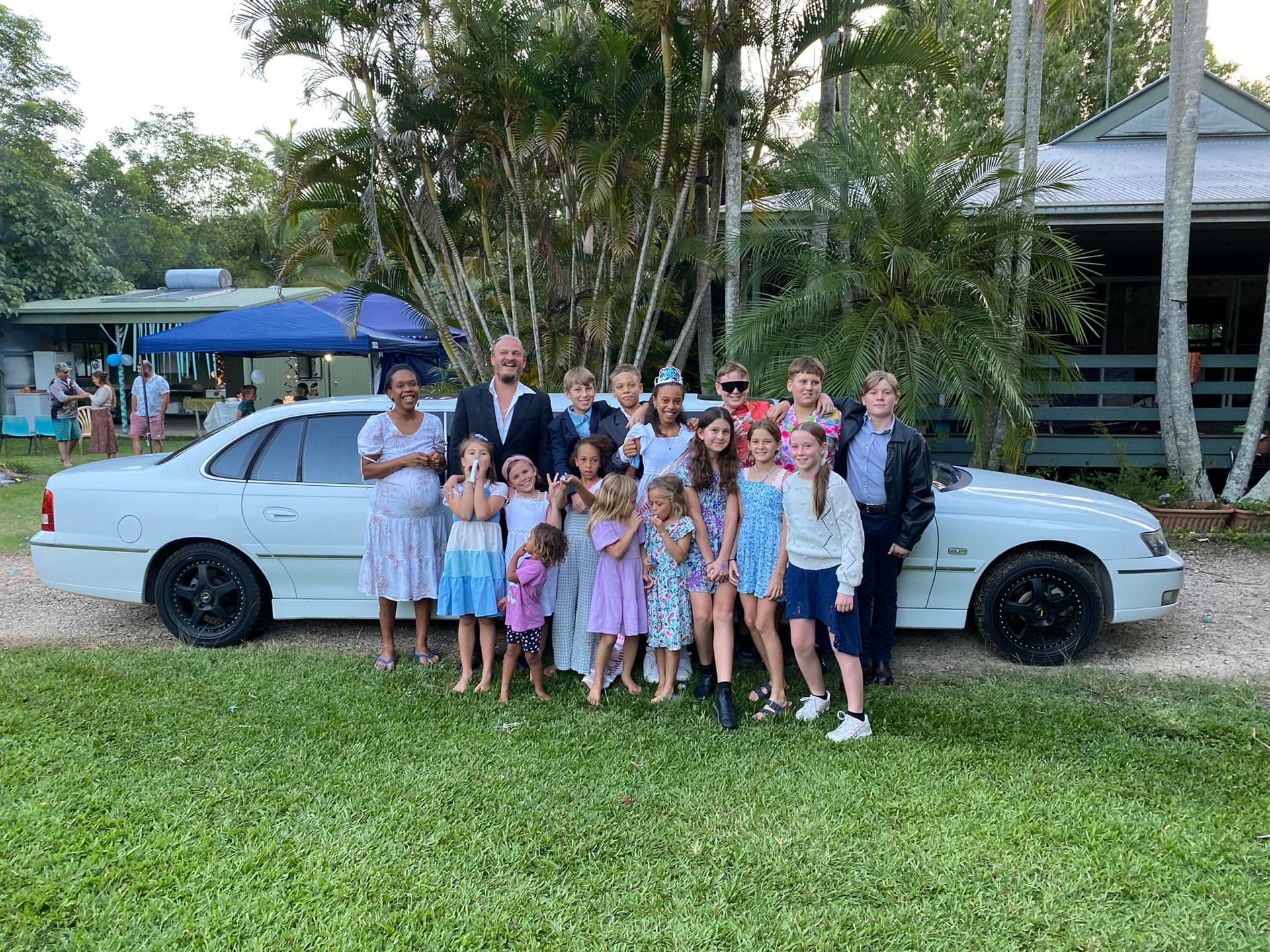 A Family is Posing for a Picture in Front of a White Limousine — Noosa Premier Stretch Holden Transfers In Sunrise Beach, QLD