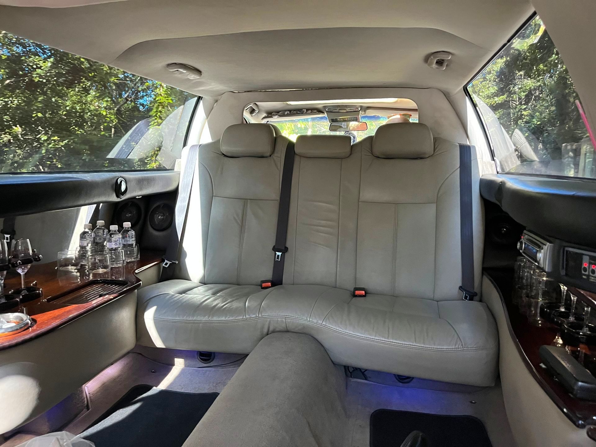 Interior And Back Seats Of a Limousine With Wine Glasses And Water Bottles, Trees Visible Outside The Window - Noosa Premier Stretch Holden Transfers In Sunrise Beach, QLD