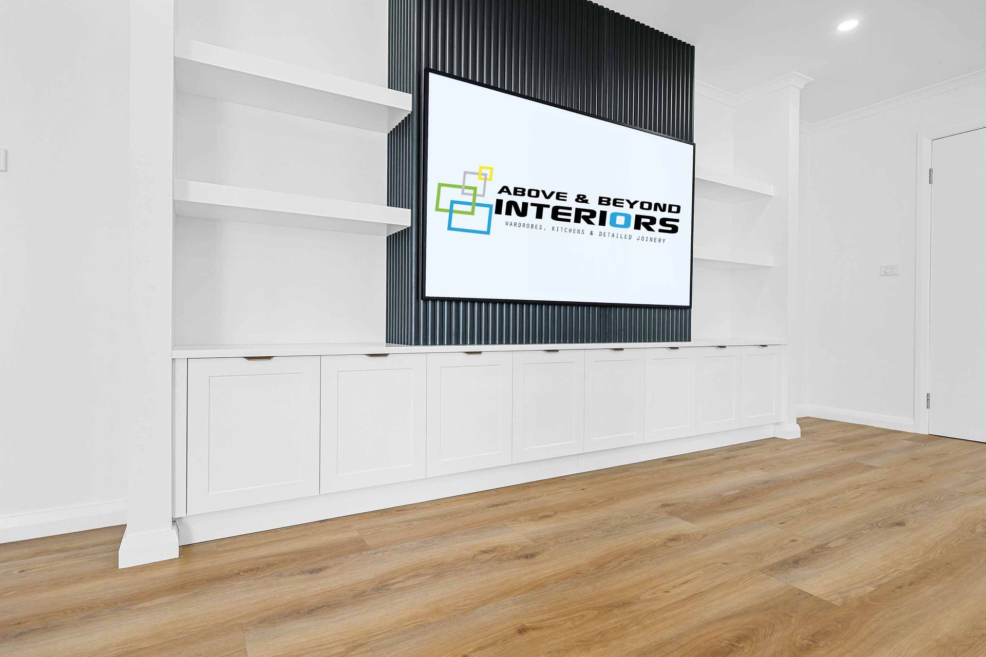 White built-in shelves and cabinets with a TV mounted on a black textured wall, over a wooden floor — Above & Beyond Interiors in Smeaton Grange, NSW