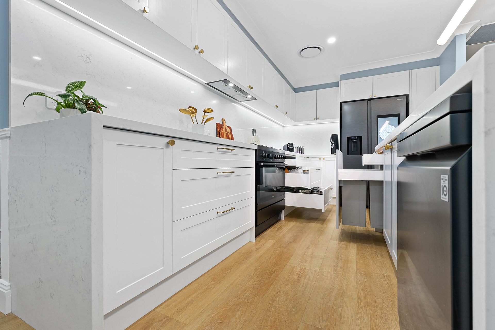 Modern white kitchen with wooden floors, stainless steel appliances, and light blue accents — Above & Beyond Interiors in Narellan, NSW