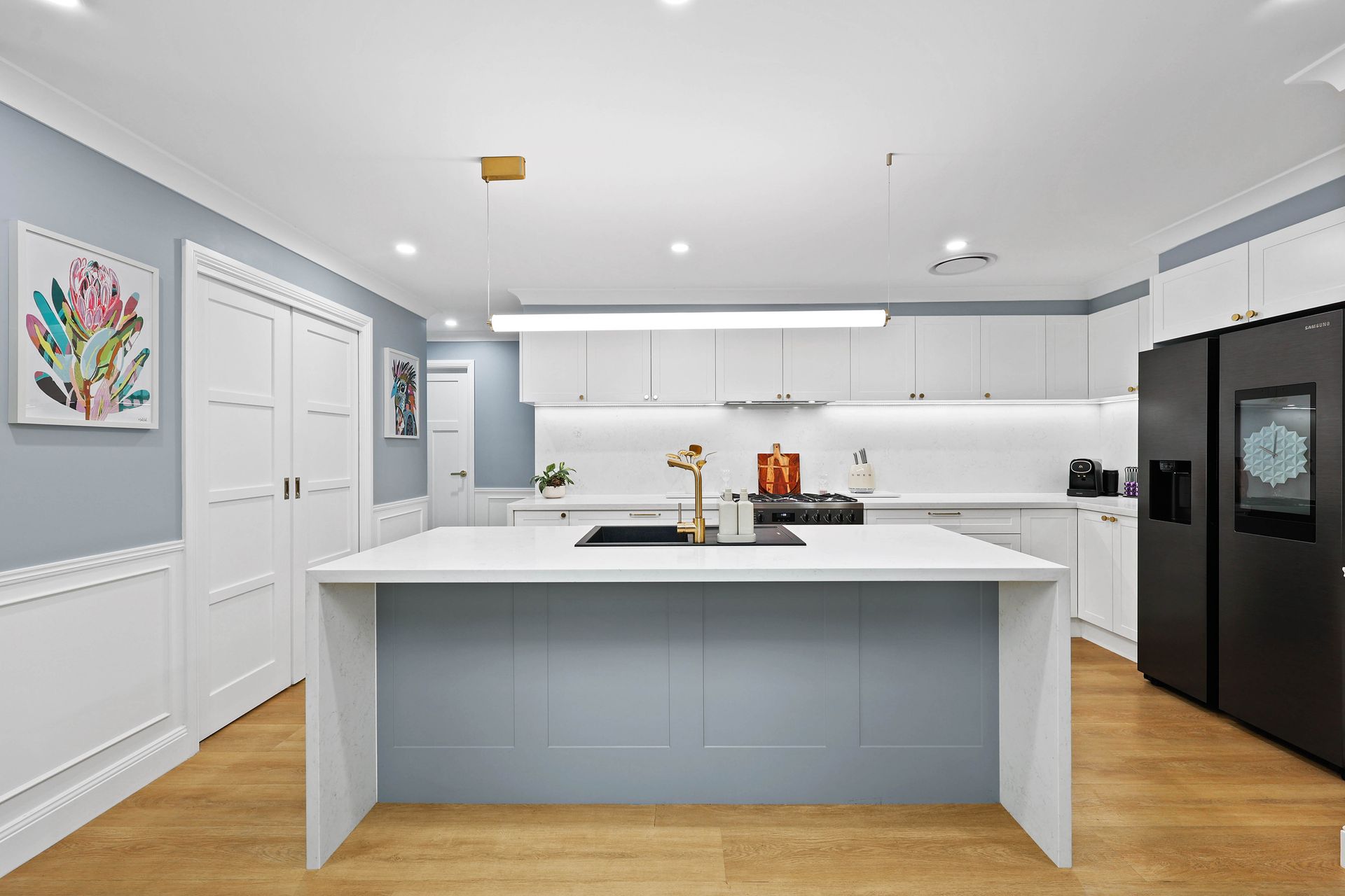 Modern white and blue kitchen with island, stainless appliances, and artwork — Above & Beyond Interiors in Narellan, NSW