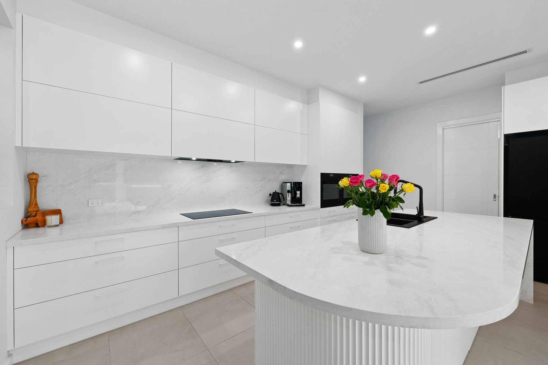 Modern white kitchen with island, countertop, and roses  — Above & Beyond Interiors in Smeaton Grange, NSW