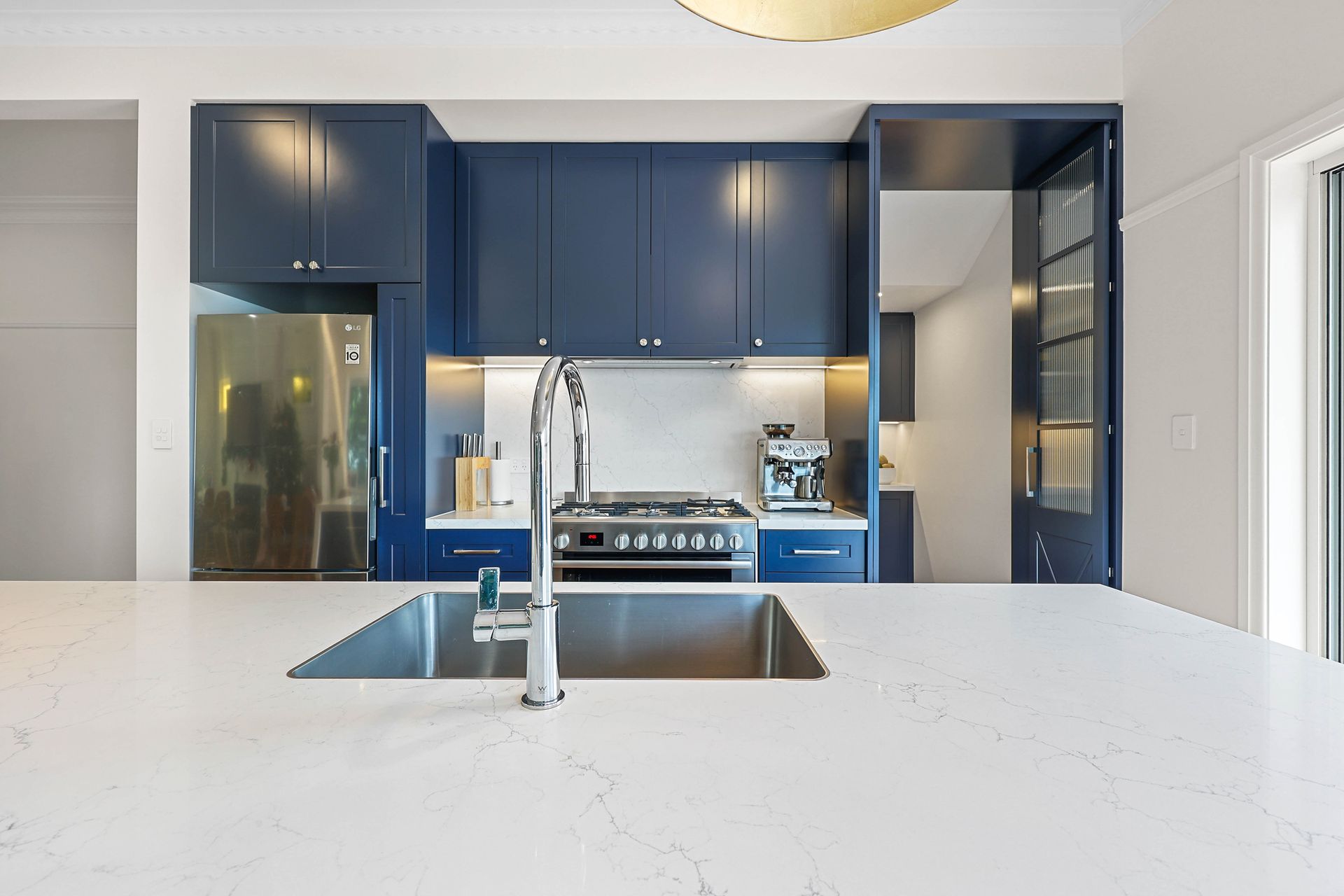 Modern kitchen with blue cabinets, stainless steel sink, and white countertop — Above & Beyond Interiors in Narellan, NSW