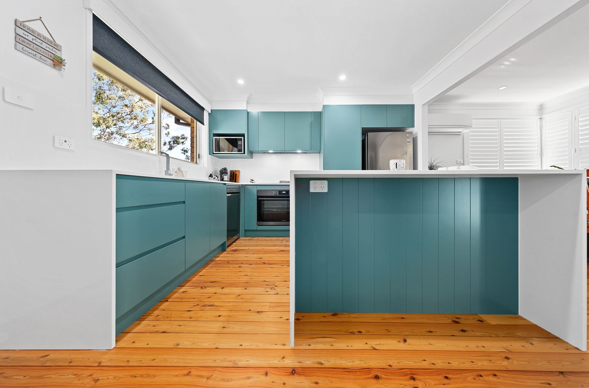 Teal kitchen with wooden floors and white accents. Island with built-in oven and cabinets — Above & Beyond Interiors in Southern Highlands, NSW