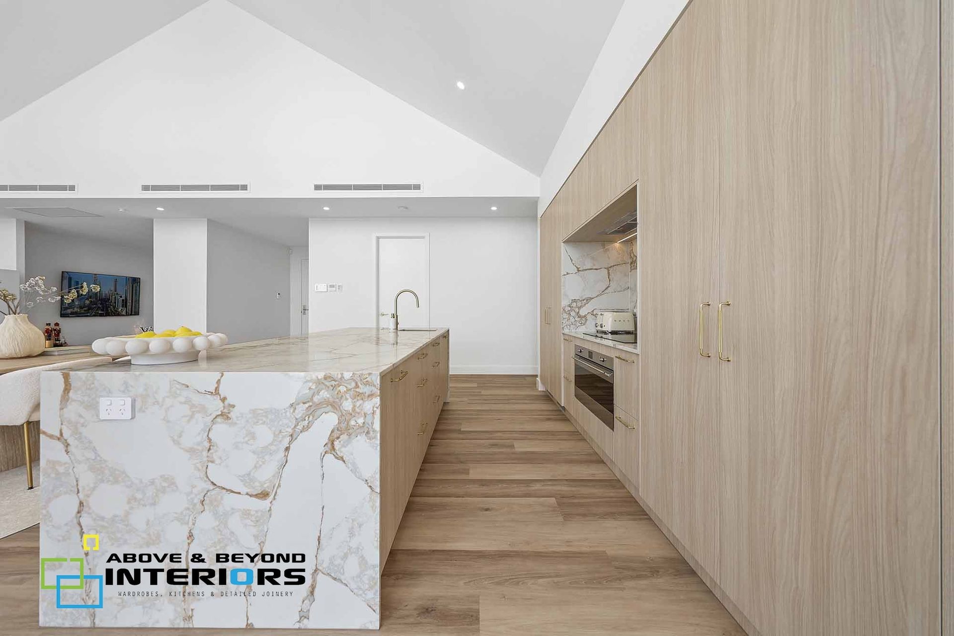 Modern Kitchen With Marble Island, Wood Cabinets, and Light Wood Flooring. — Above & Beyond Interiors in Smeaton Grange, NSW