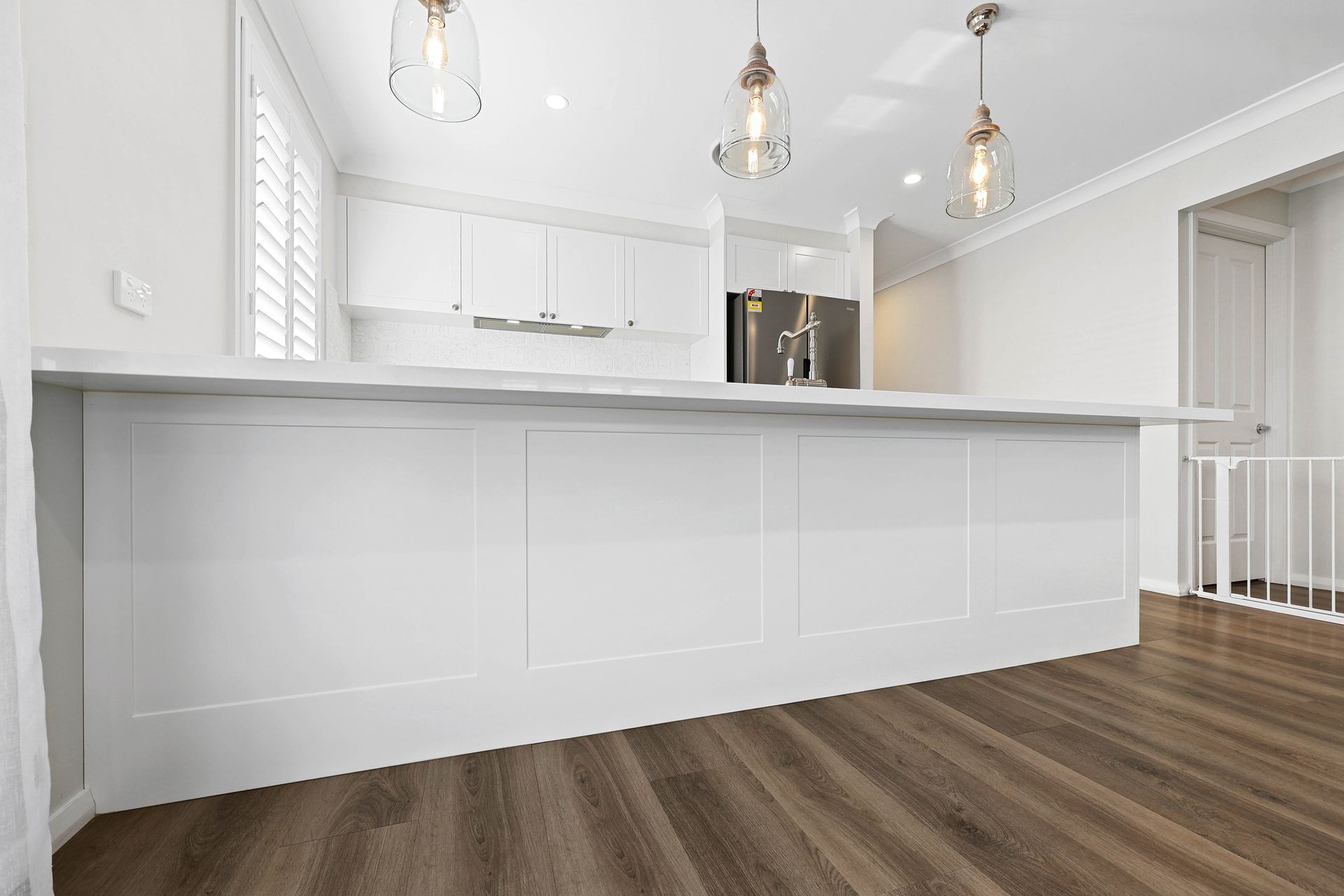A White Kitchen with Dark Wood Flooring — Above & Beyond Interiors in Smeaton Grange, NSW