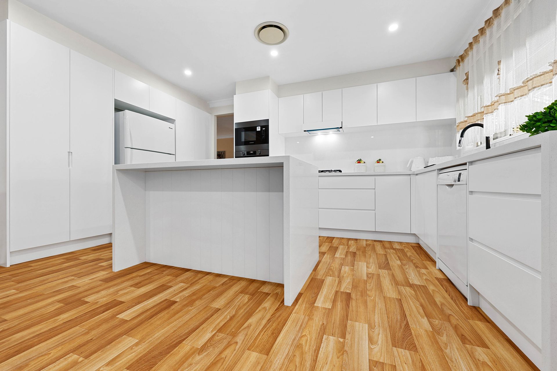 A Kitchen with Wood Floors and A Central Island — Above & Beyond Interiors in Smeaton Grange, NSW