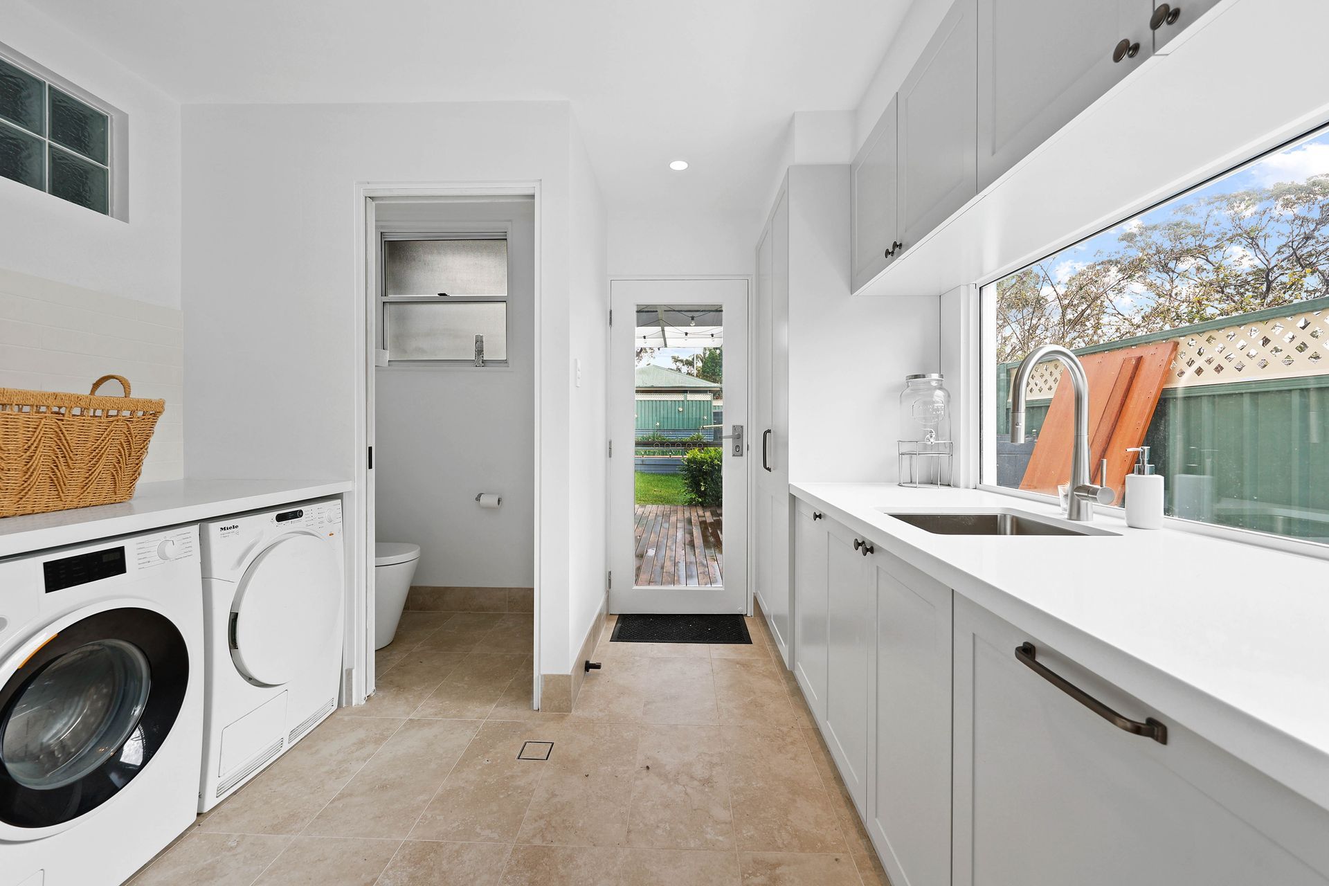 Bright Laundry Room and Kitchen with White Cabinets — Above & Beyond Interiors in Smeaton Grange, NSW