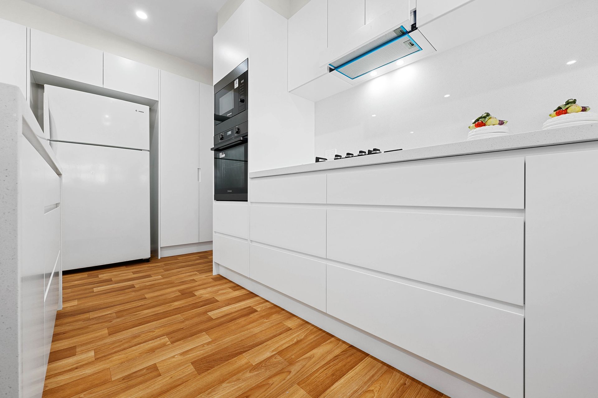 A Kitchen with Cabinets, Wood Floor, and A Refrigerator — Above & Beyond Interiors in Smeaton Grange, NSW