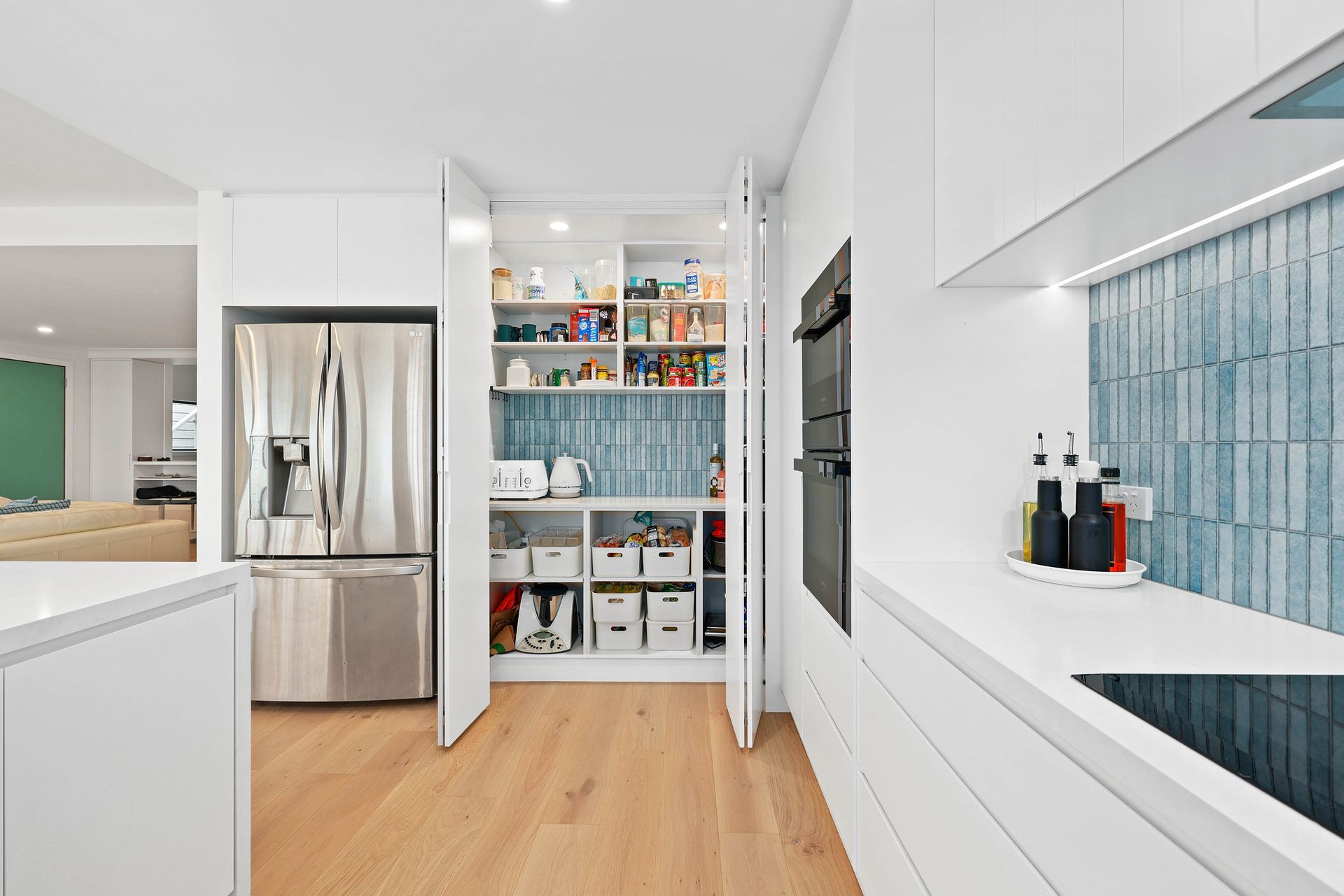 Bright White Kitchen Hallway with Stainless Fridge — Above & Beyond Interiors in Smeaton Grange, NSW