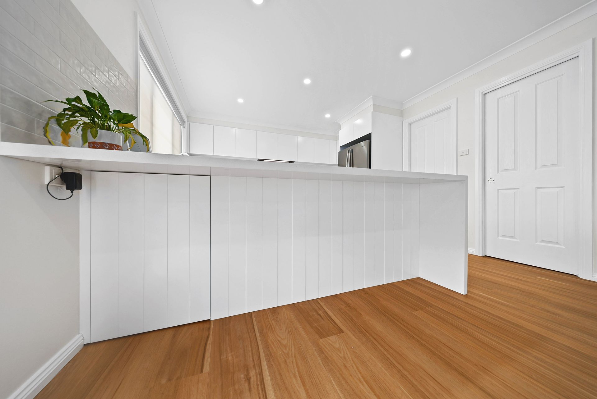 Bright White Kitchen with Breakfast Bar — Above & Beyond Interiors in Smeaton Grange, NSW