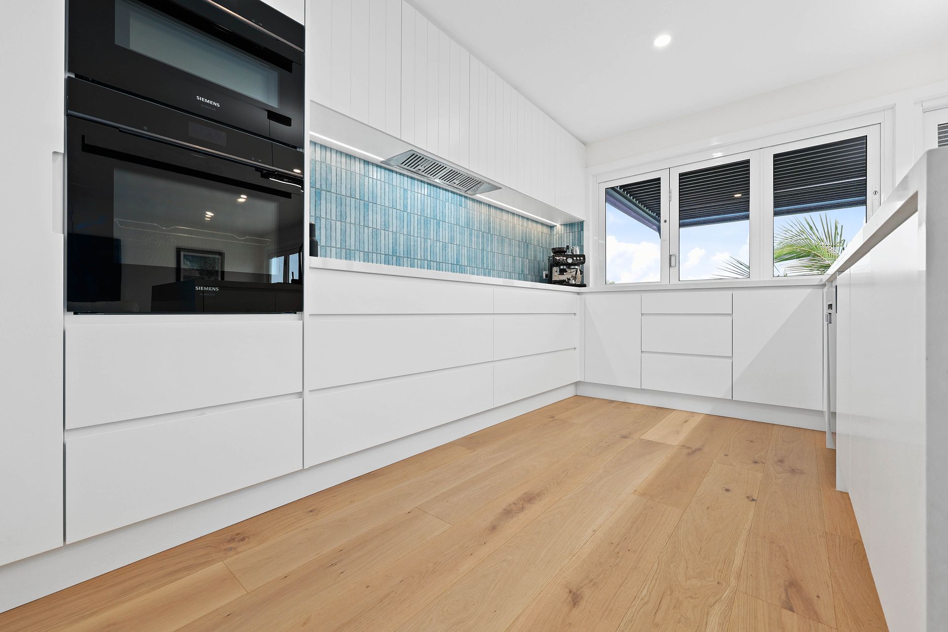 Modern White Kitchen with Light Wood Floor — Above & Beyond Interiors in Smeaton Grange, NSW