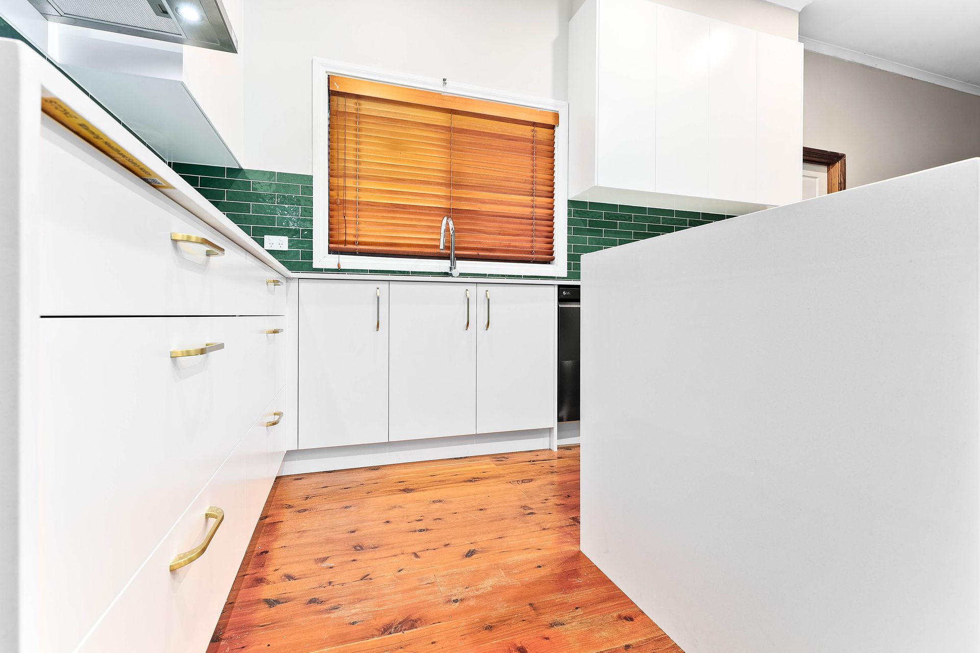 A White Kitchen with Wooden Floor, Green Backsplash, and A Window — Above & Beyond Interiors in Smeaton Grange, NSW
