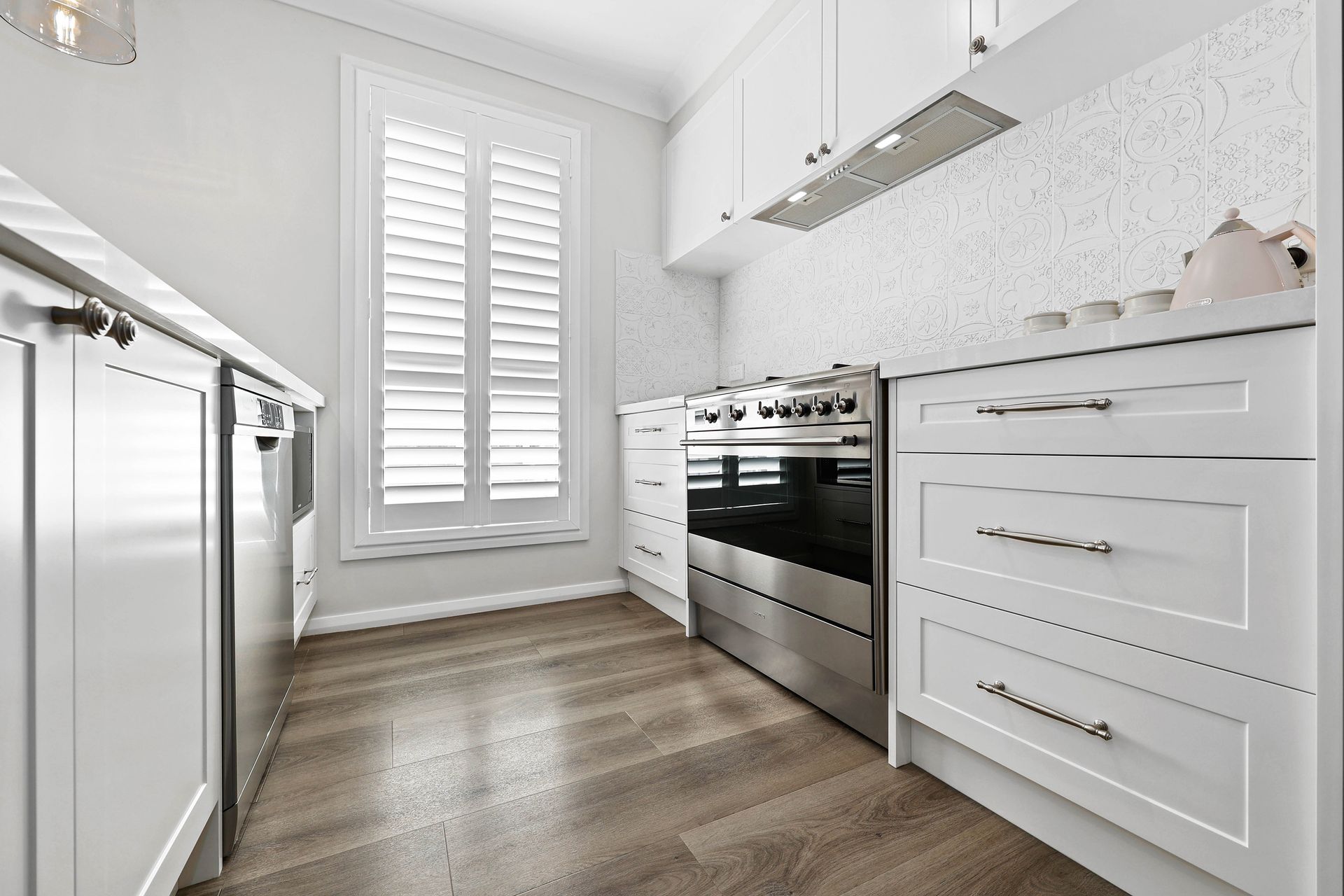 Bright White Modern Kitchen with Stainless Steel Oven — Above & Beyond Interiors in Smeaton Grange, NSW