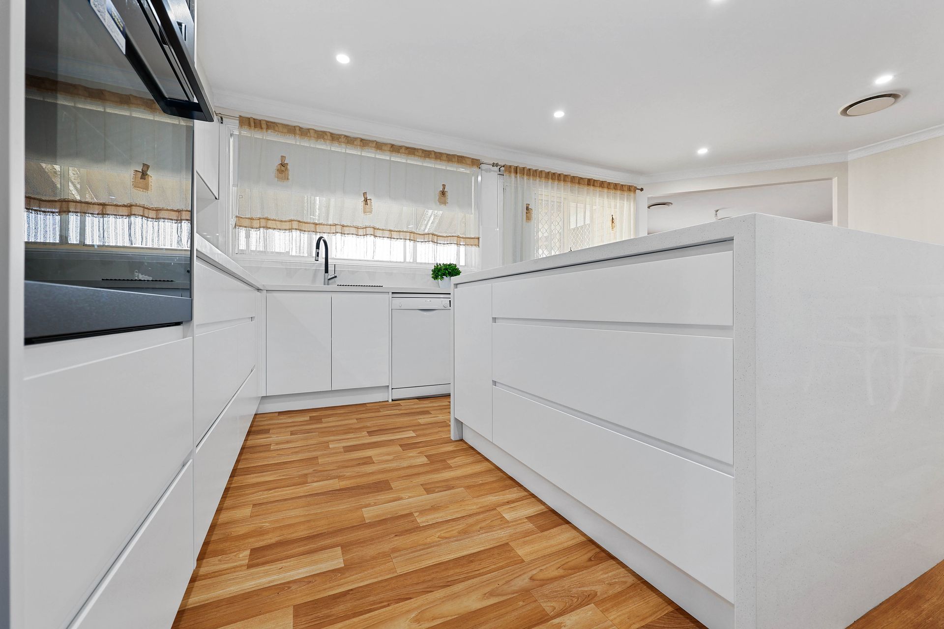 A Kitchen with Wood Flooring and Built-In Appliances — Above & Beyond Interiors in Smeaton Grange, NSW