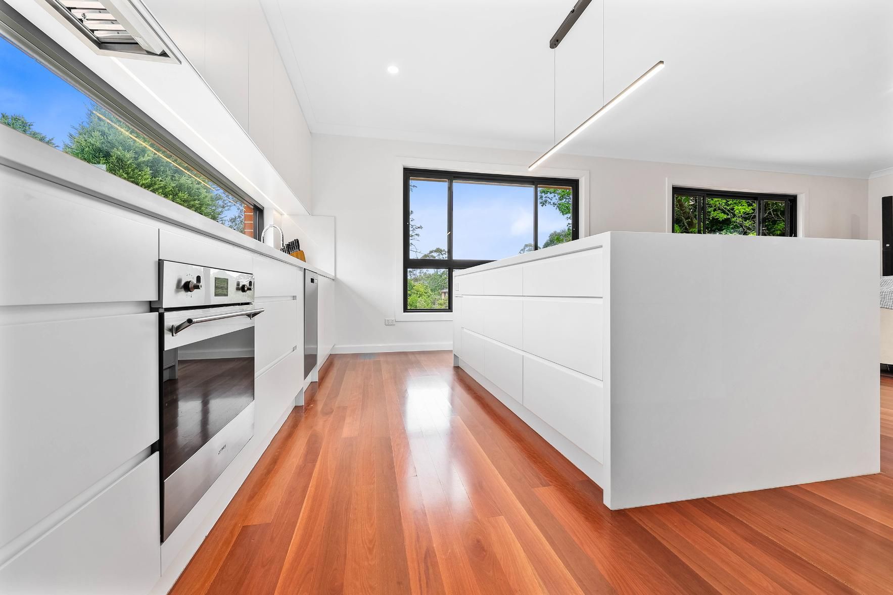 Modern White Kitchen with Wood Floors — Above & Beyond Interiors in Smeaton Grange, NSW