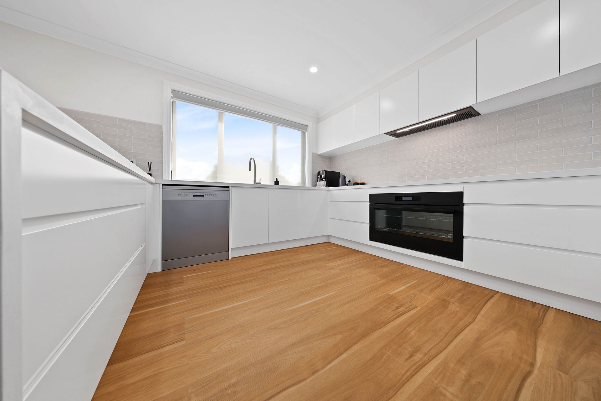 Bright Modern White Kitchen with Wood Floor — Above & Beyond Interiors in Smeaton Grange, NSW
