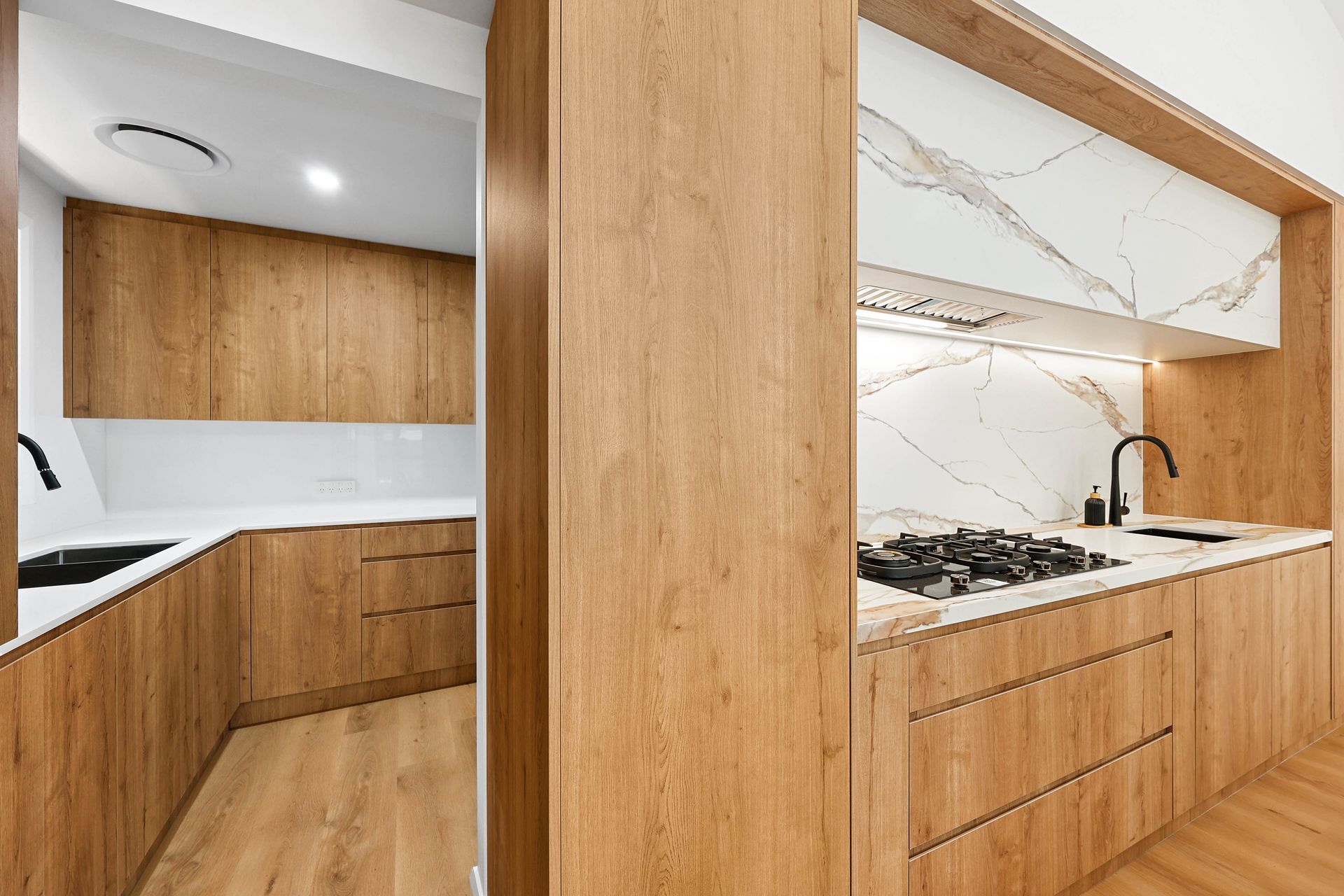 A Kitchen with Wood Cabinets, Marble Backsplash, and Countertops — Above & Beyond Interiors in Smeaton Grange, NSW