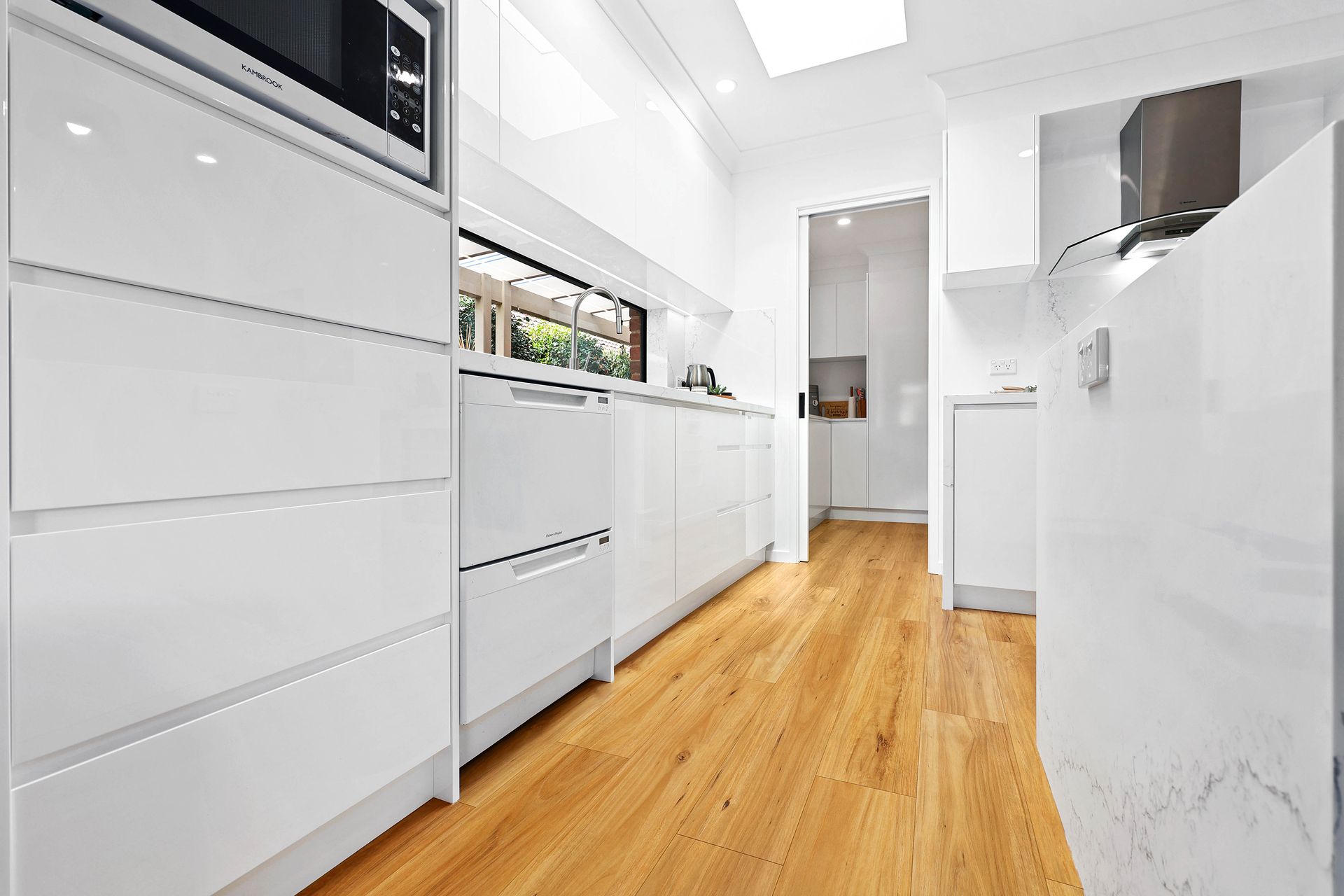 Bright White Modern Kitchen with Wood Floors and Built-In Appliances — Above & Beyond Interiors in Smeaton Grange, NSW