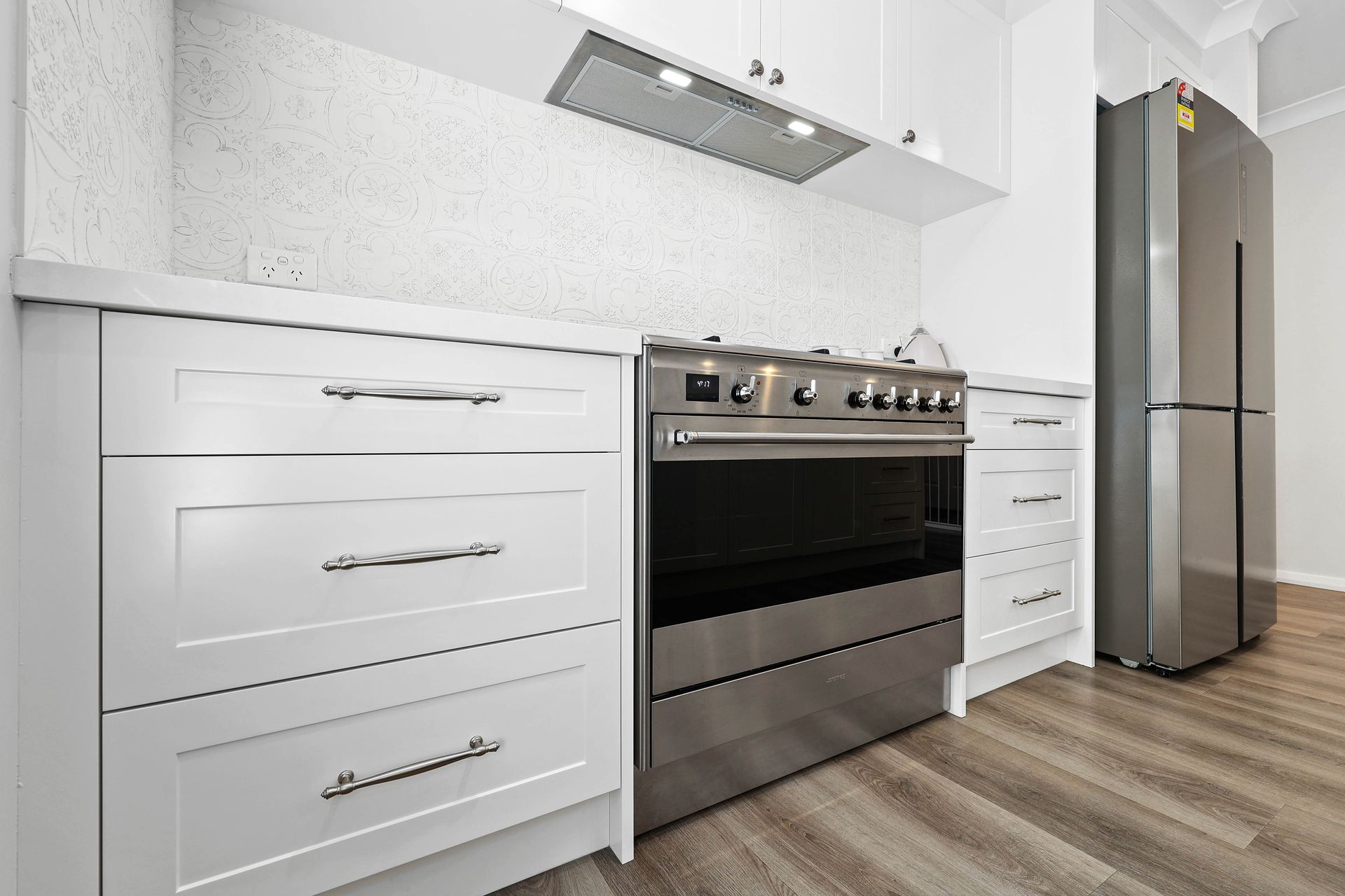Modern White Kitchen with Stainless Steel Stove — Above & Beyond Interiors in Smeaton Grange, NSW