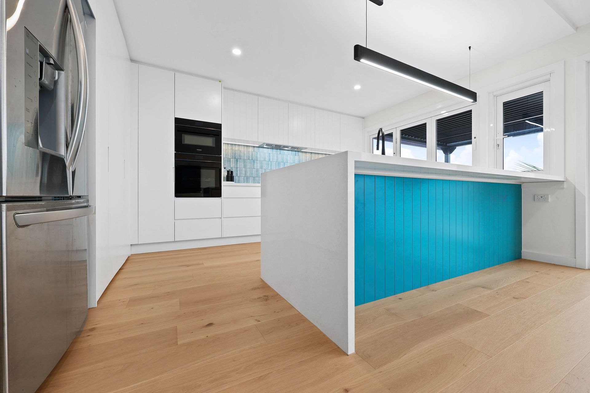 Bright Modern Kitchen with White Cabinets and A Turquoise Island Divider — Above & Beyond Interiors in Smeaton Grange, NSW