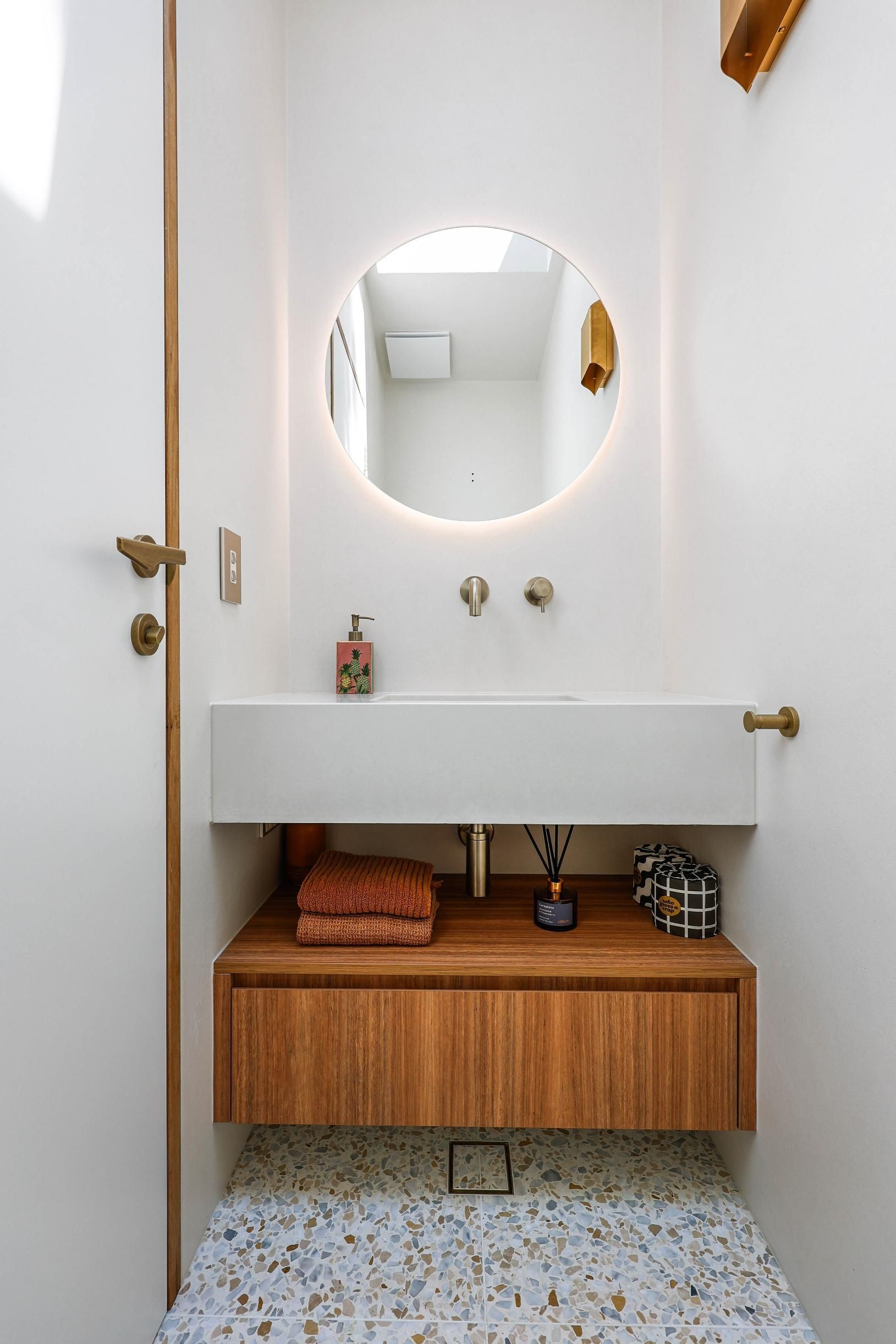 Small White Bathroom Vanity With Round Mirror, Sink, Wooden Cabinet — Above & Beyond Interiors in Smeaton Grange, NSW