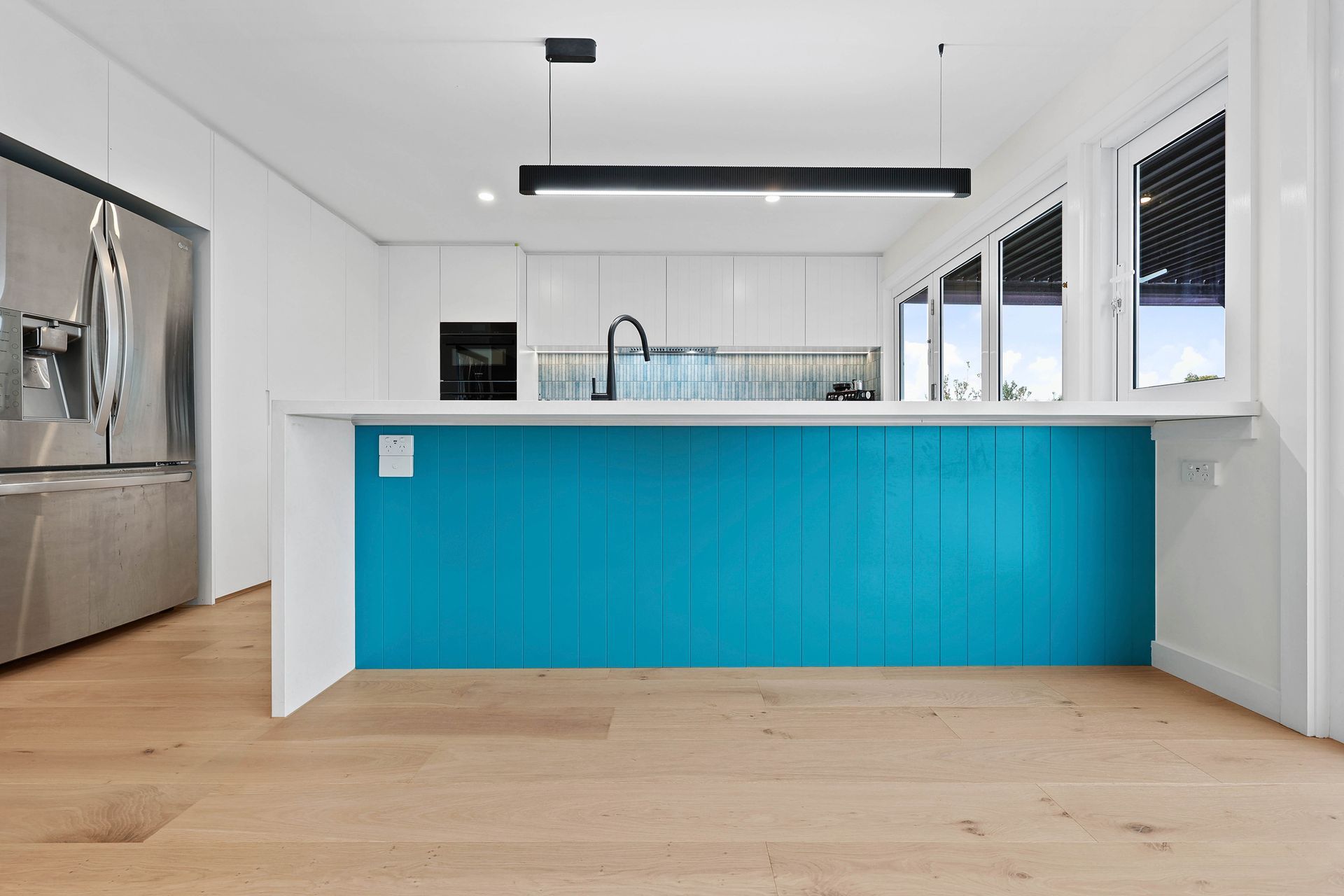 A Kitchen with Bright Blue Island, White Cabinets, and Wood Floors — Above & Beyond Interiors in Smeaton Grange, NSW