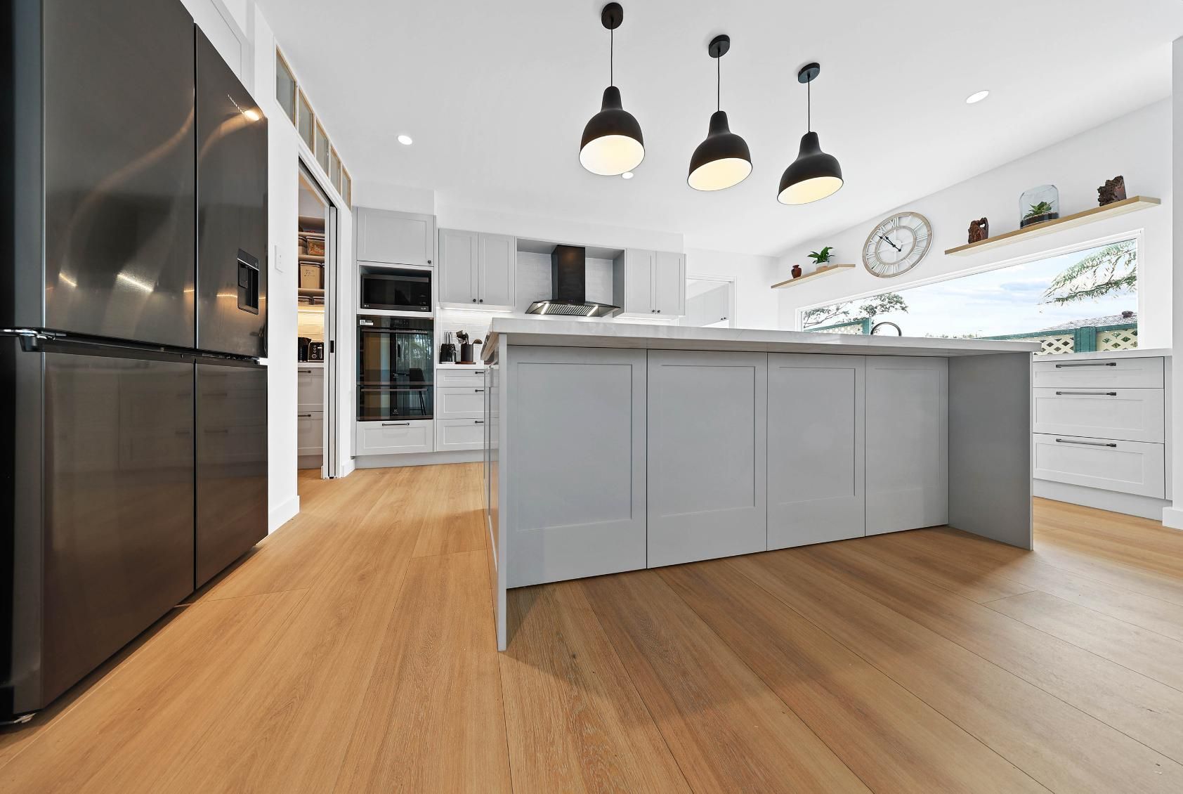 A Kitchen with Gray Island, Black Pendant Lights and Stainless Steel Appliances — Above & Beyond Interiors in Smeaton Grange, NSW